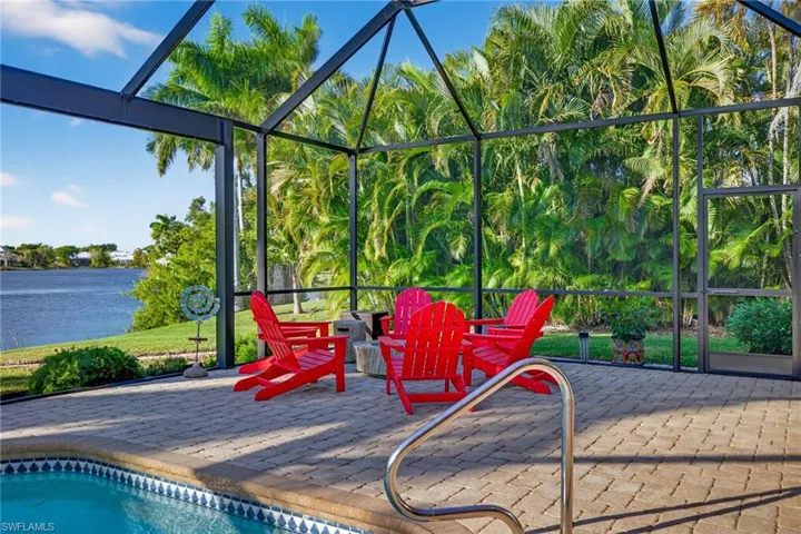 Swimming pool with screen enclosure, a water view, and a patio area