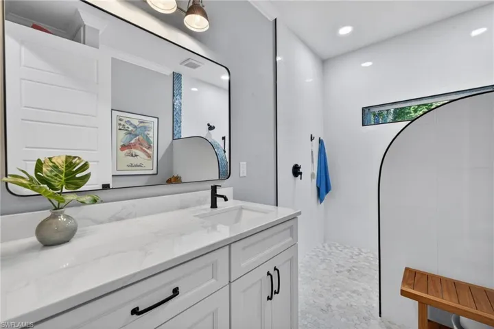 Bathroom featuring a walk in shower, vanity, and recessed lighting
