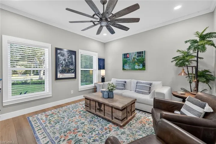 Living room with wood finished floors, recessed lighting, ornamental molding, and ceiling fan
