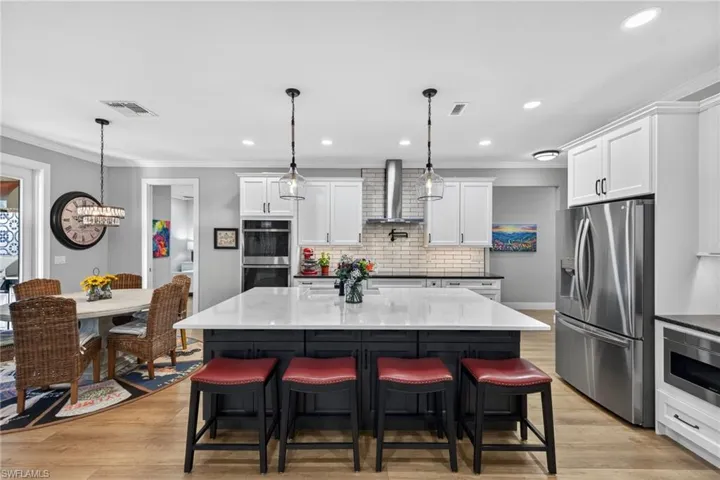 Kitchen featuring appliances with stainless steel finishes, ornamental molding, recessed lighting, dark stone countertops, and pendant lighting