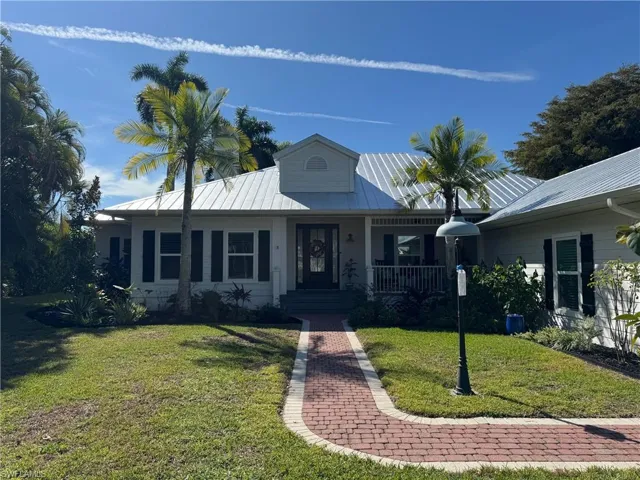 View of front of property with a porch, a front yard, and a metal roof