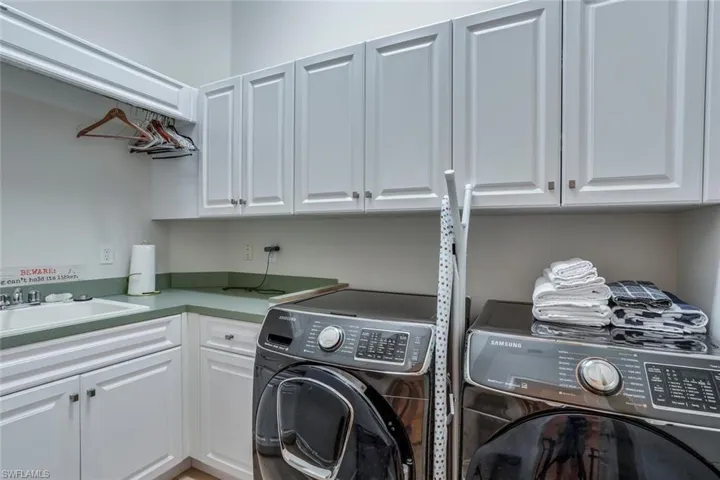 Clothes washing area with cabinets, separate washer and dryer, and sink