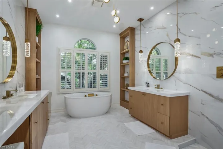 Bathroom featuring vanity, a bath, and tile walls