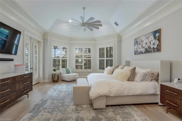 Bedroom with light hardwood / wood-style floors, vaulted ceiling, ceiling fan, and ornamental molding
