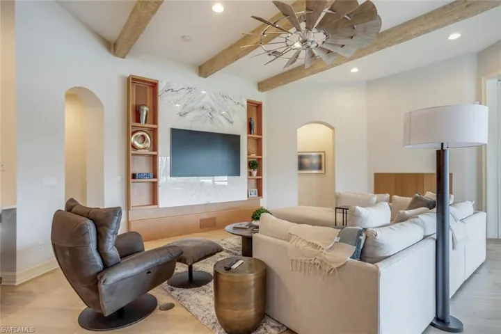 Living room featuring beamed ceiling, light hardwood / wood-style flooring, and ceiling fan