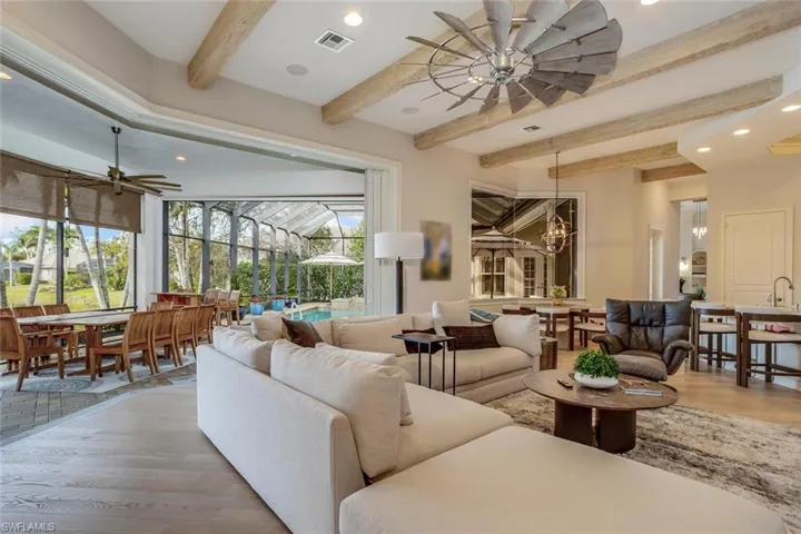 Living room featuring hardwood / wood-style floors, ceiling fan, beam ceiling, and a healthy amount of sunlight