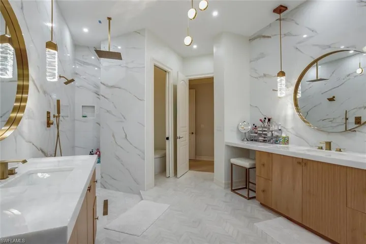 Bathroom featuring tiled shower, vanity, and toilet