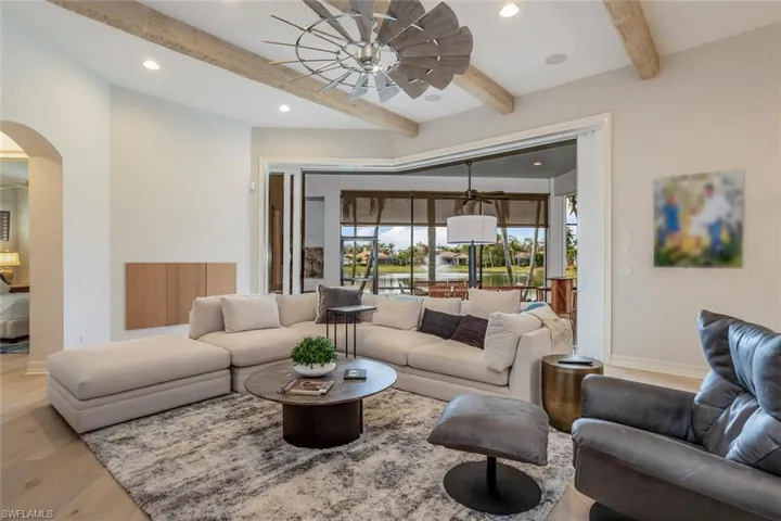 Living room with beamed ceiling, ceiling fan, and light hardwood / wood-style flooring