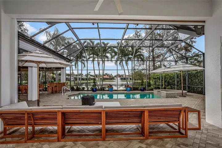 View of pool with a lanai, ceiling fan, a bar, and a patio