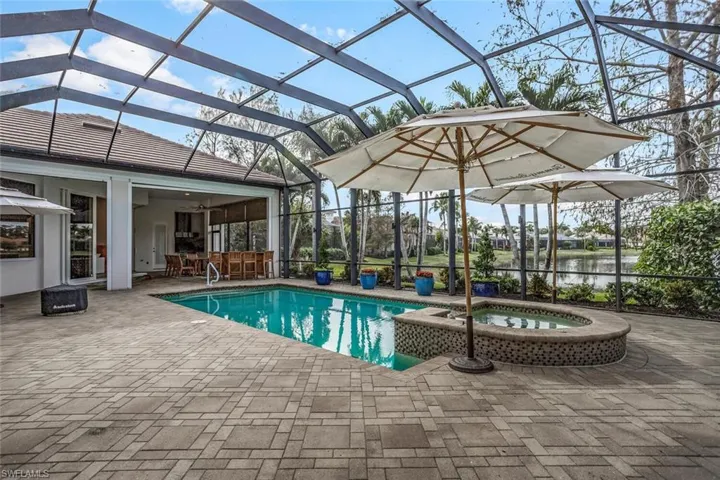 View of pool featuring a lanai, a patio area, a water view, and exterior bar