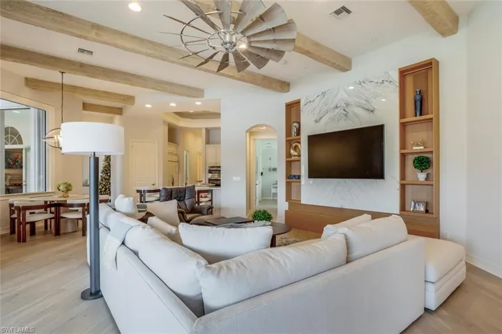 Living room featuring beamed ceiling, ceiling fan, and light wood-type flooring