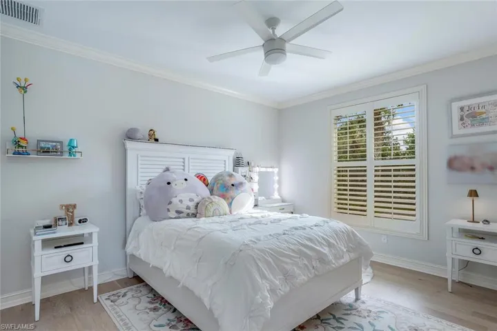 Bedroom featuring light hardwood / wood-style flooring, ceiling fan, and ornamental molding