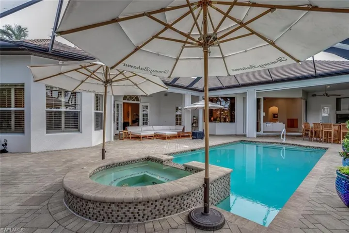 View of pool with an in ground hot tub, an outdoor hangout area, exterior bar, and a patio