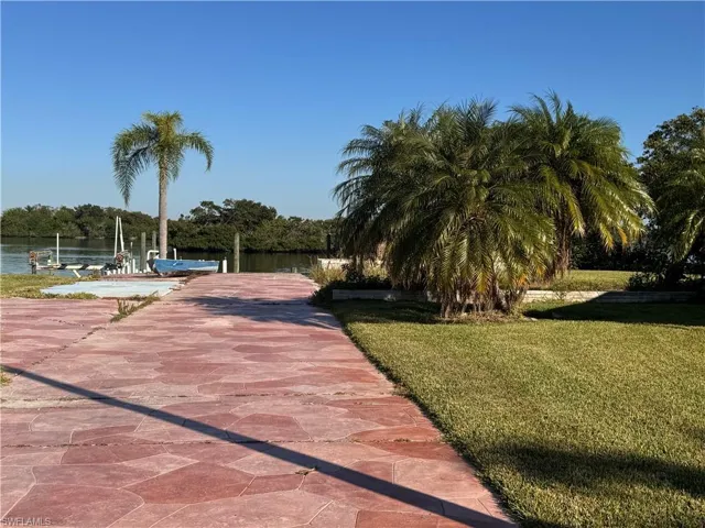 View of home's community with a lawn, a dock, and a water view