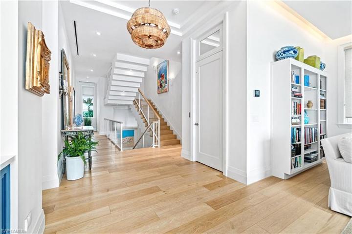 Lite and airy hardwood floors flow to the stunning hardwood staircase with glass railing that make it appear to be floating