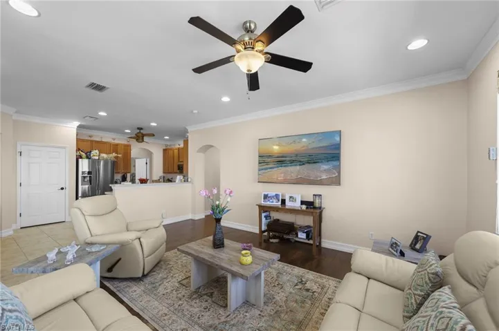 Living area with a ceiling fan, recessed lighting, ornamental molding, arched walkways, and wood finished floors