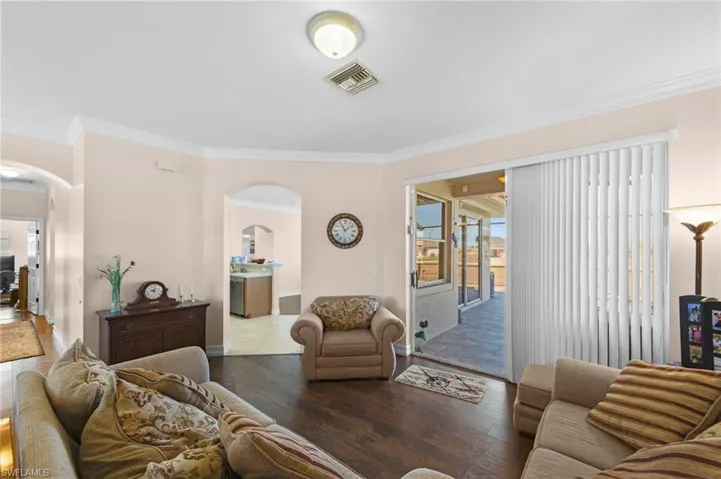 Living room with hardwood / wood-style floors, arched walkways, and ornamental molding