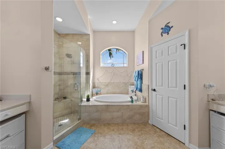 Bathroom with vanity, a shower stall, a garden tub, and light tile patterned flooring