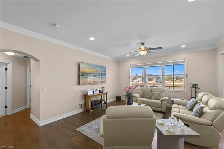 Living area featuring arched walkways, ornamental molding, wood finished floors, ceiling fan, and recessed lighting