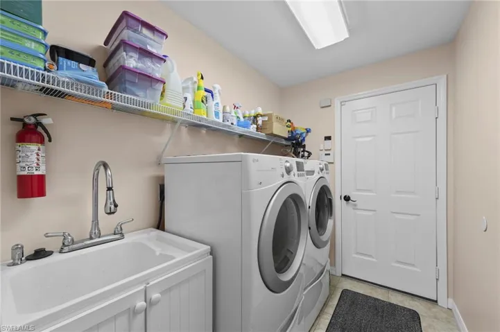 Laundry area with separate washer and dryer and light tile patterned flooring