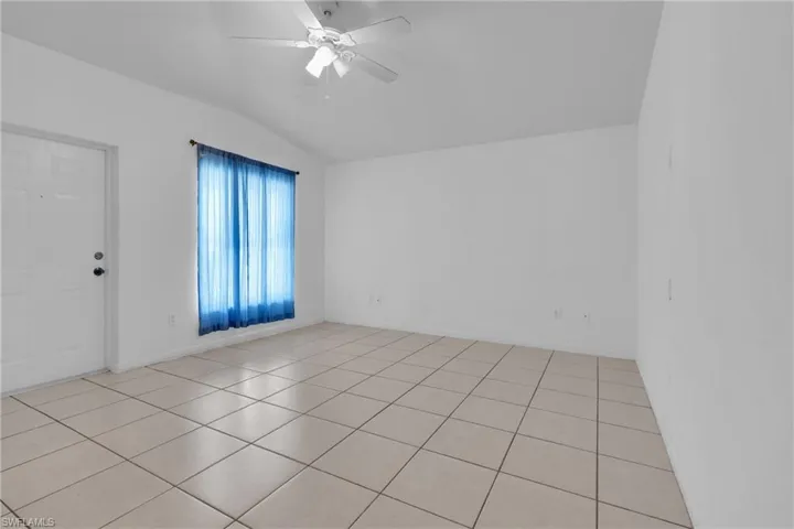 Unfurnished room featuring ceiling fan, light tile patterned floors, and lofted ceiling