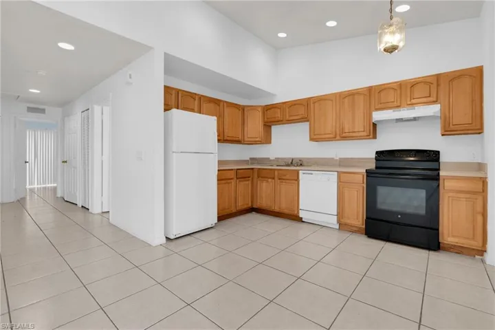 Kitchen with white appliances, light countertops, and light tile patterned floors