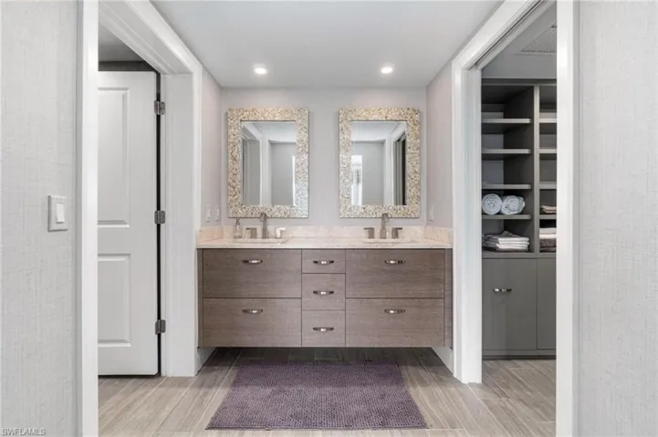 Full bath with double vanity, light wood finished floors, and recessed lighting
