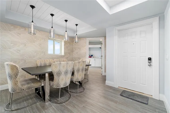 Dining space with a raised ceiling, light wood-type flooring, a skylight, and wood ceiling