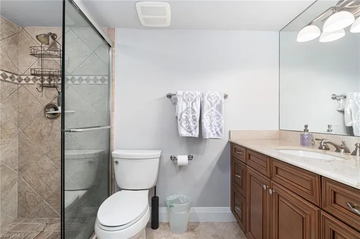 Full bathroom featuring a stall shower, vanity, and light tile patterned floors