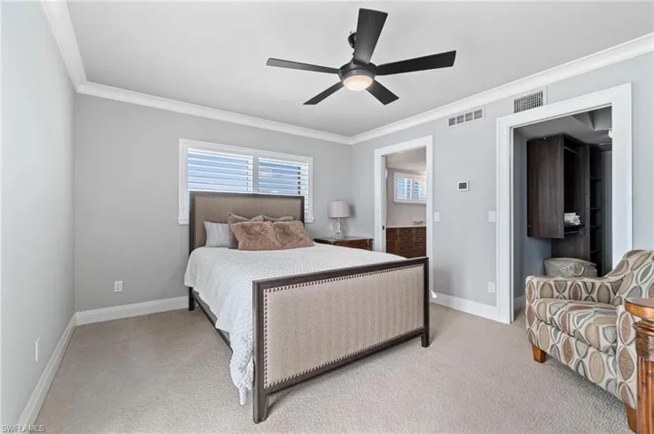 Bedroom with ornamental molding, carpet floors, connected bathroom, and ceiling fan