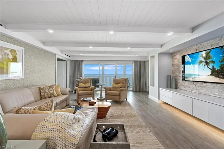 Living area featuring healthy amount of natural light, wood finished floors, and beamed ceiling