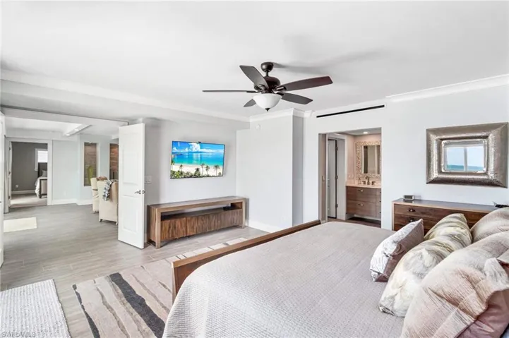 Bedroom with wood finished floors, crown molding, ceiling fan, and ensuite bathroom