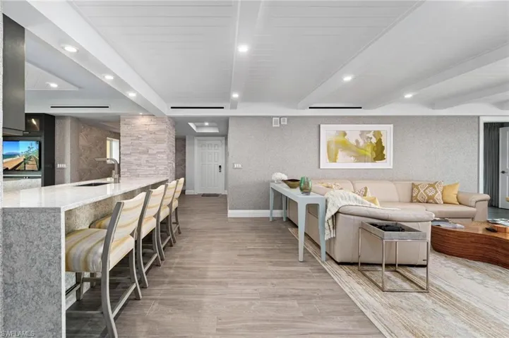 Living room with light wood-style flooring, beamed ceiling, recessed lighting, and wallpapered walls
