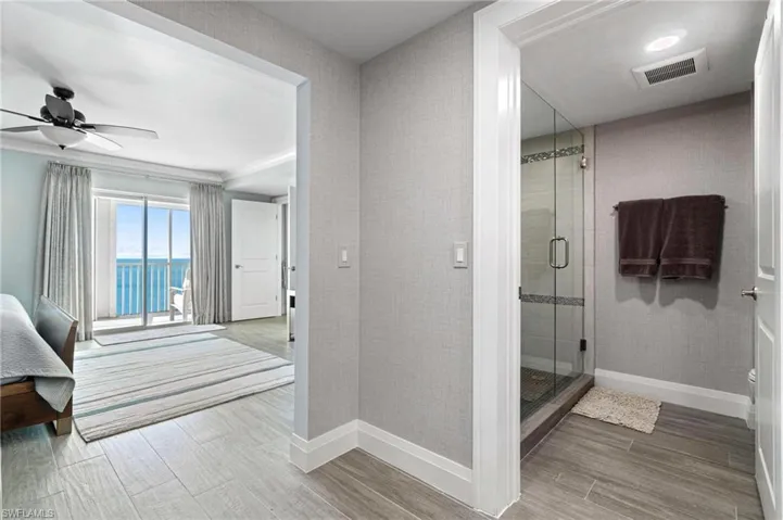 Bathroom featuring light wood-style floors, a shower stall, ceiling fan, and a water view