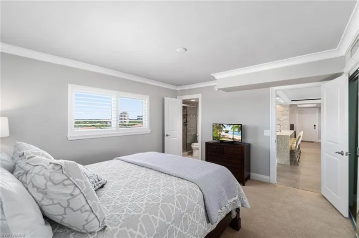 Bedroom with ornamental molding, light colored carpet, and ensuite bathroom