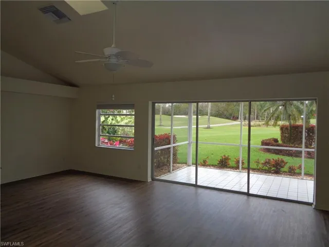 Empty room featuring dark wood finished floors, lofted ceiling, golf course view, and a ceiling fan