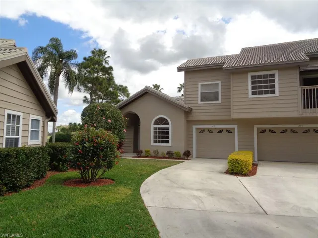 View of front of house with a front yard, concrete driveway, an attached garage, and stucco siding