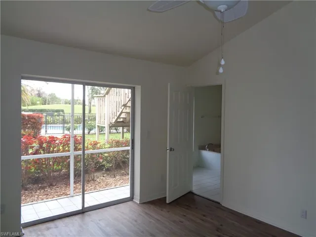 Empty room with wood finished floors, lofted ceiling, and ceiling fan