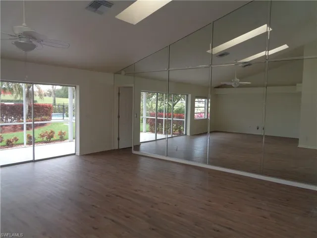 Unfurnished bedroom with access to outside, ceiling fan, dark wood-type flooring, and lofted ceiling