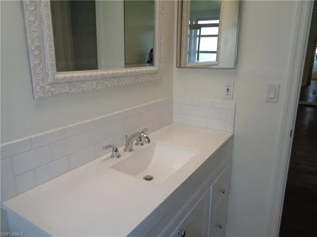 Bathroom with vanity and tasteful backsplash