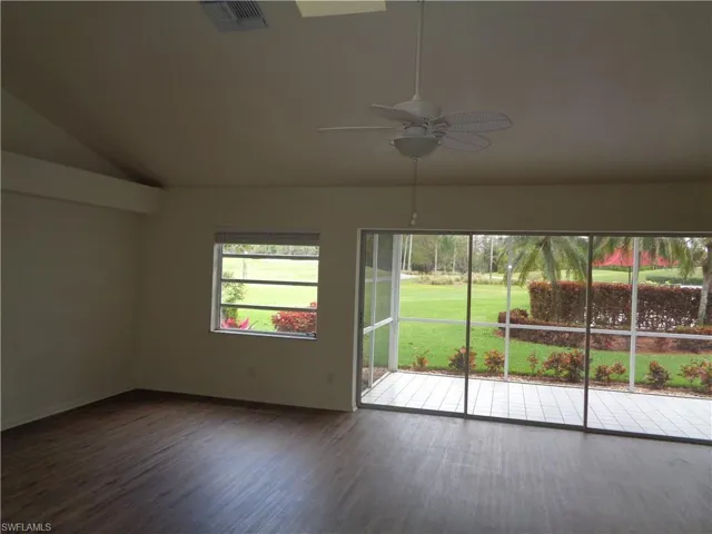 Spare room featuring dark wood-style flooring, lofted ceiling, and a ceiling fan