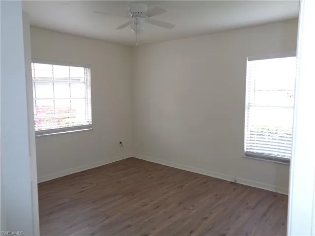 Empty room with dark wood-type flooring and ceiling fan