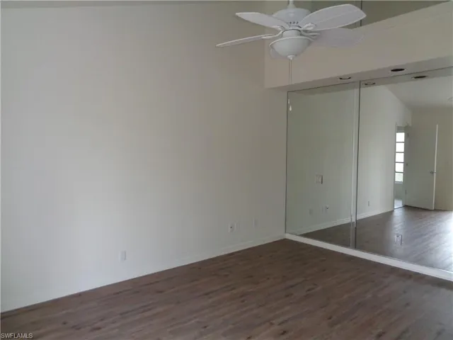 Unfurnished bedroom with dark wood-style flooring, ceiling fan, and a closet