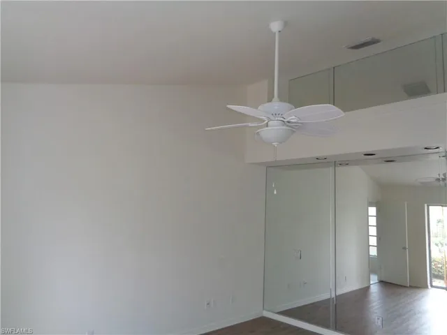 Unfurnished room with dark wood-style flooring and a ceiling fan