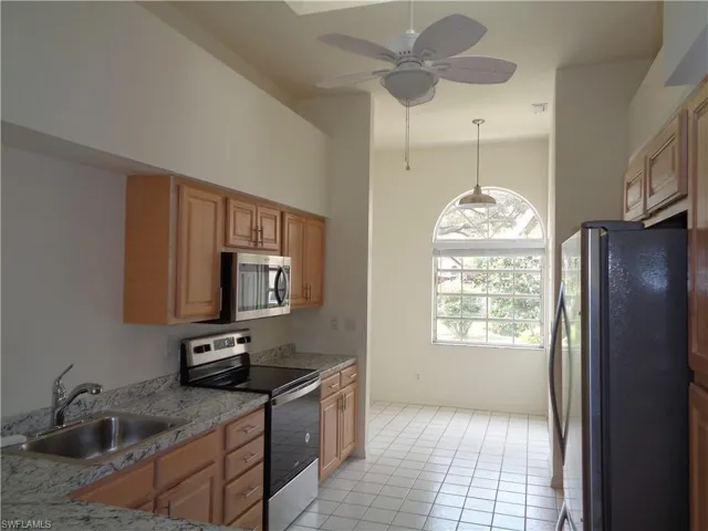 Kitchen with appliances with stainless steel finishes, light tile patterned floors, a skylight, hanging light fixtures, and ceiling fan