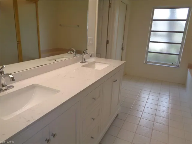 Full bath featuring double vanity and light tile patterned flooring