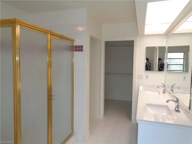 Bathroom with double vanity, a walk in closet, a stall shower, and light tile patterned flooring