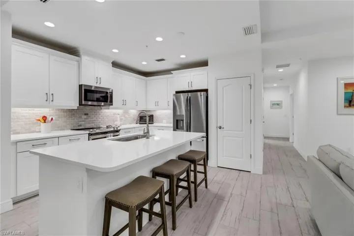 Kitchen featuring white cabinets, sink, a kitchen bar, and stainless steel appliances