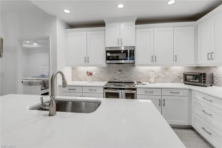 Kitchen with white cabinetry, sink, tile backsplash, and stainless steel appliances