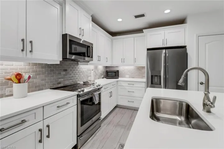 Kitchen with white cabinets, stainless steel appliances, sink, and tile backsplash
